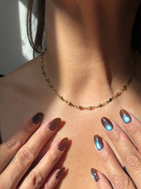 A stainless steel gold PVD star chain choker necklace, hanging on a model’s neck 
