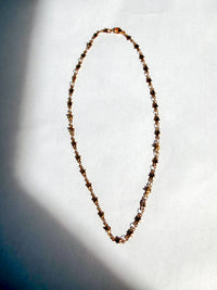 A photo of a stainless steel gold PVD star chain choker necklace laid on a flat background 